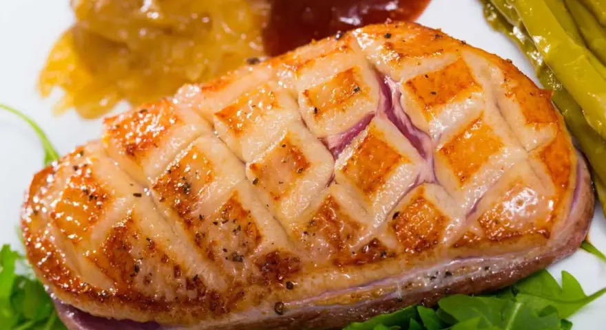 Magret de pato perfectamente cocinado, con piel crujiente y jugoso por dentro, acompañado de espárragos y compota.