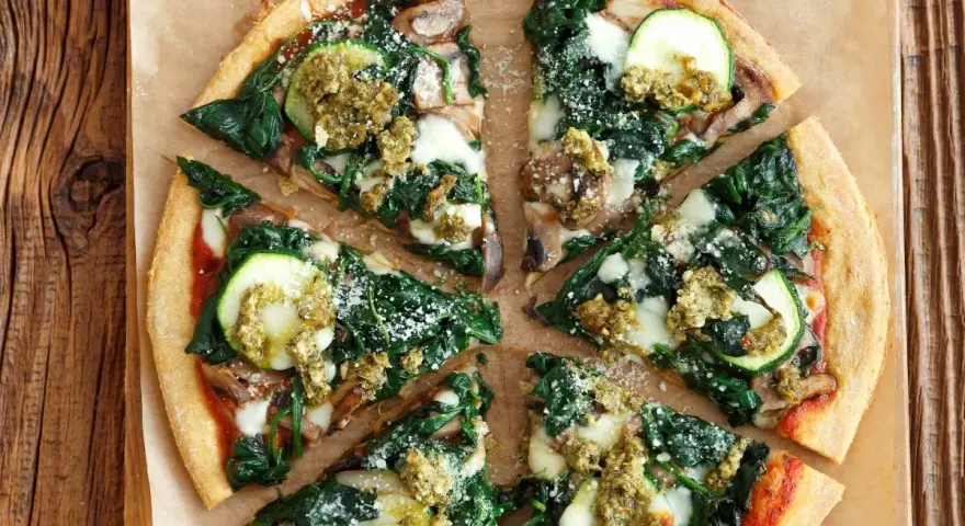 Pyszna pizza ze szpinakiem, cukinią i pieczarkami, polana zielonym pesto. Idealna na lekki obiad.