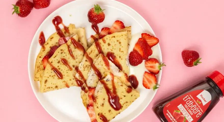 Zarte crepes ohne zucker, garniert mit frischen Erdbeeren und Erdbeer-Topping. Ein Genuss für alle, die es süß, aber zuckerarm mögen.