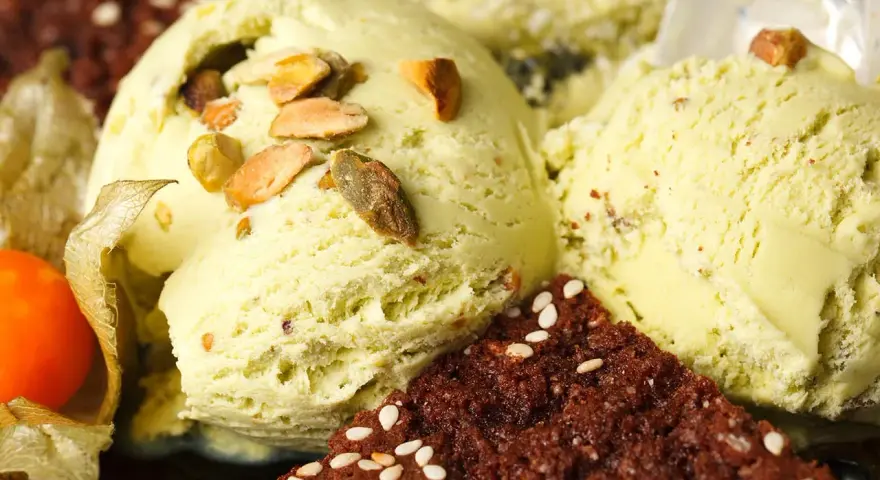 Veganes Eis selber machen: Cremiges Pistazieneis mit Nüssen und Schokostückchen, garniert mit Physalis.
