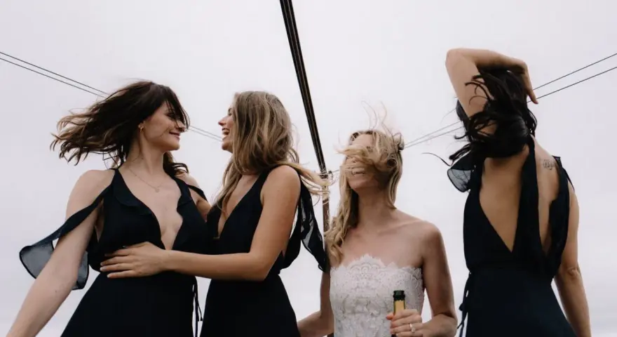 Sorelle della sposa, con abiti neri eleganti, celebrano il matrimonio con champagne. Accessori per abito nero matrimonio perfetti per un look sofisticato.