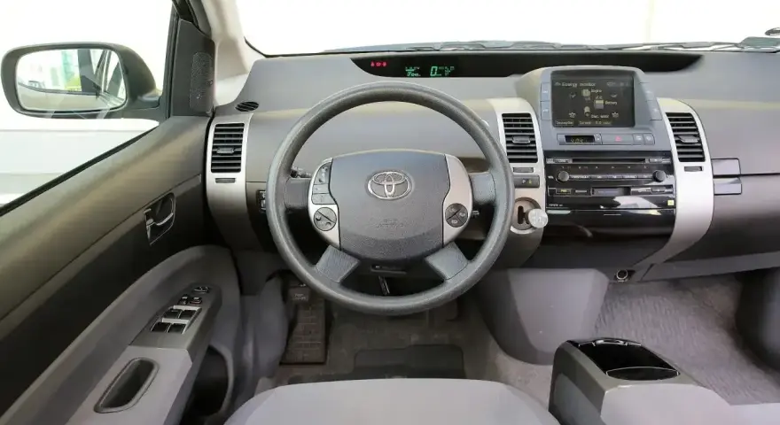 Wnętrze Toyoty Prius 2 z kierownicą, panelem radia i ekranem.