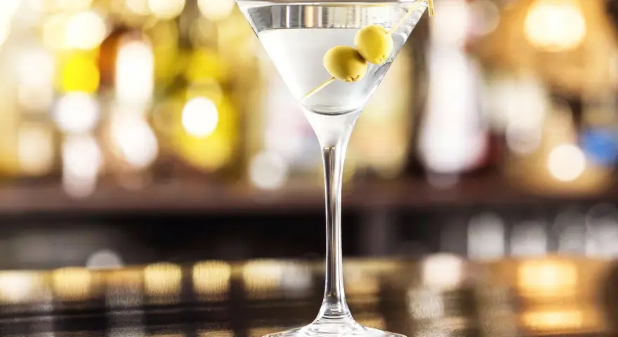Elegancki gin z wermutem, ozdobiony dwiema oliwkami, czeka na Ciebie przy barze.