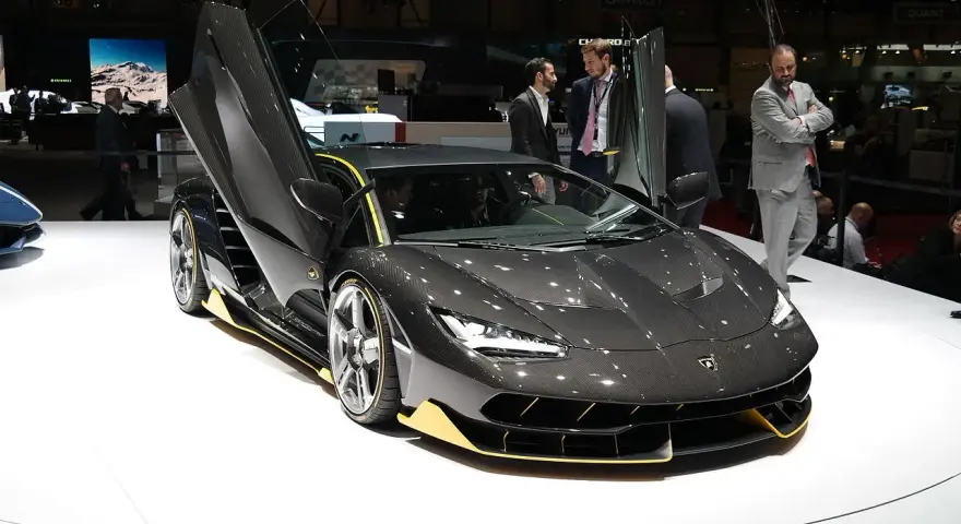 Ciemnoszary Lamborghini z otwartymi drzwiami, żółte akcenty. Zastanawiasz się, ile kosztuje Lamborghini Urus? Ten model to marzenie.