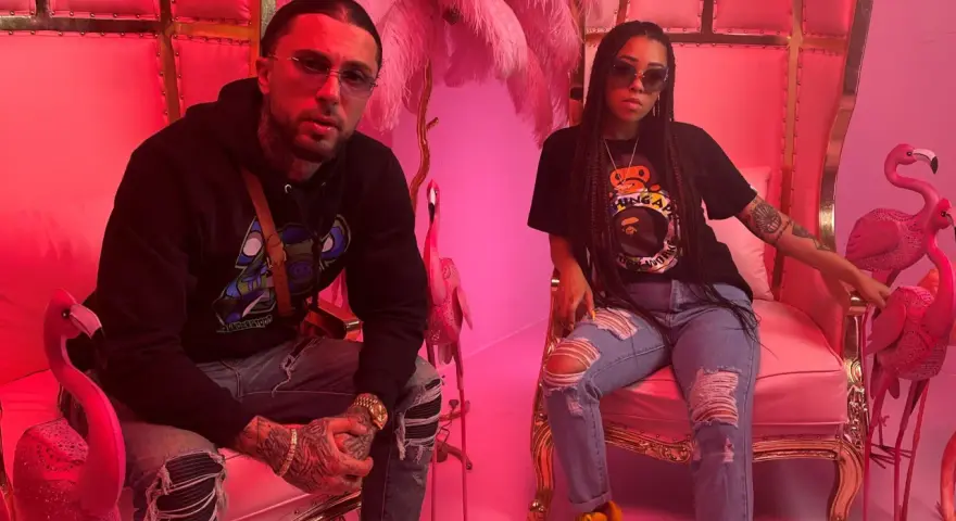 Malik Montana i jego towarzyszka w różowych tronach, otoczeni flamingami. Czuć klimat jetlagu i luksusu.