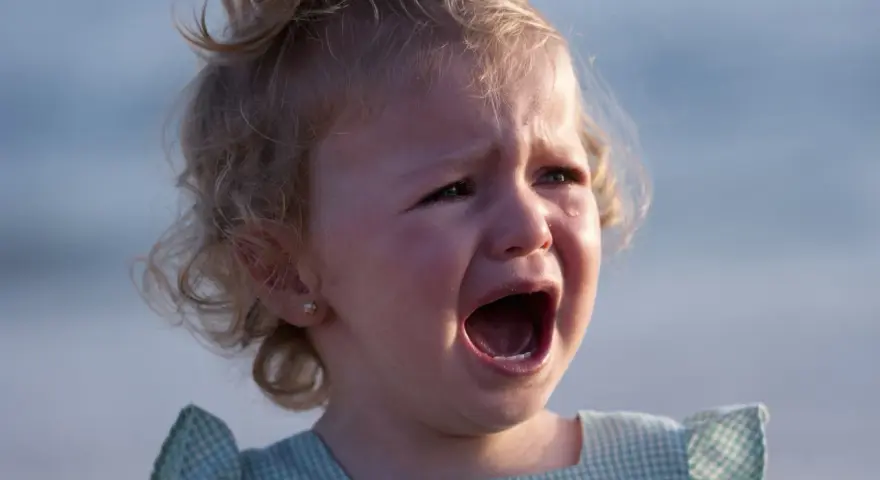 Ein kleines Mädchen mit blonden Locken weint bitterlich. Tränen laufen über ihre Wangen. Wahrscheinlich ist sie mitten in der Trotzphase mit 2 Jahren.