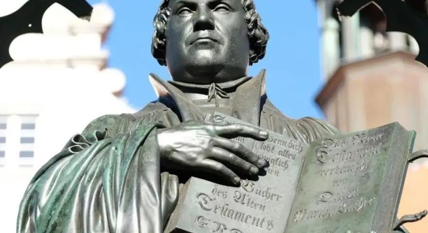 Martin Luther hält eine Bibel. Er erinnert uns daran, wer am Reformationstag frei hat.