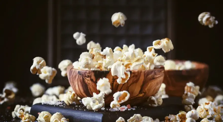 Chrupiący popcorn w drewnianej misce, unoszący się w powietrzu. Czy zastanawiałeś się nad jego indeksem glikemicznym?