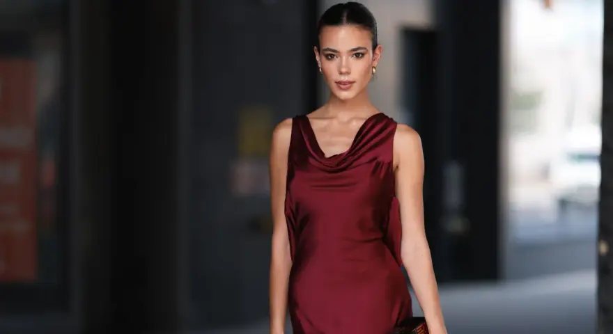 Una mujer elegante con un vestido burdeos satinado, ideal para saber como combinar un vestido burdeos para una boda.