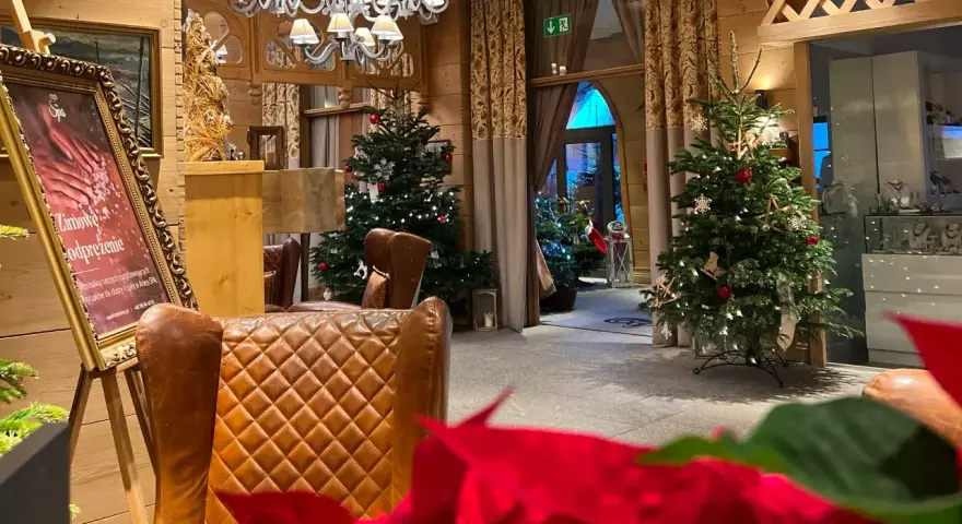 Przytulne wnętrze z choinkami i wygodnymi fotelami, idealne na pobyt z kolacją wigilijną.