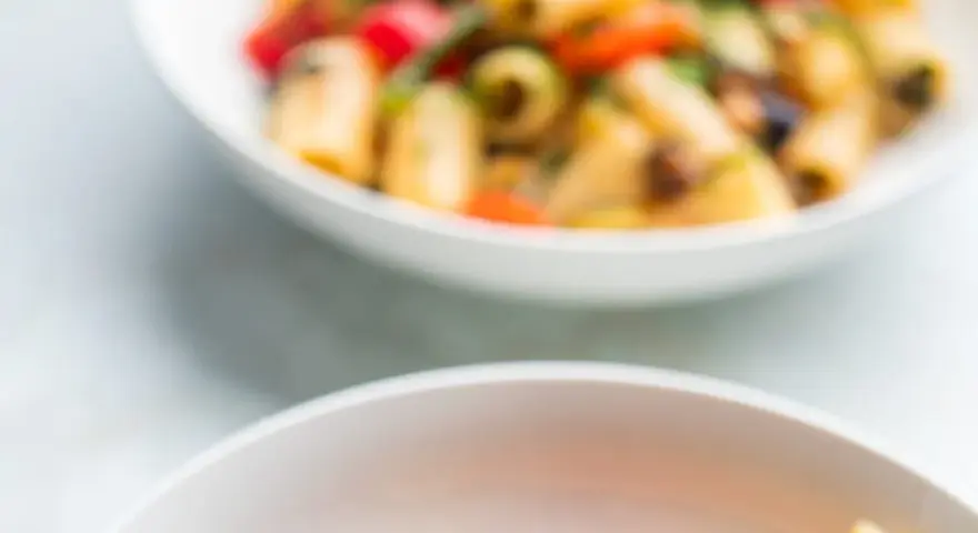 Due ciotole bianche piene di pasta con verdure colorate, un piatto estivo invitante.