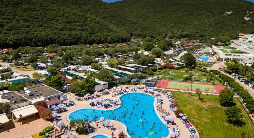 Wakacje na **camping Oliva** to baseny, korty tenisowe i mnóstwo zieleni pod górą.