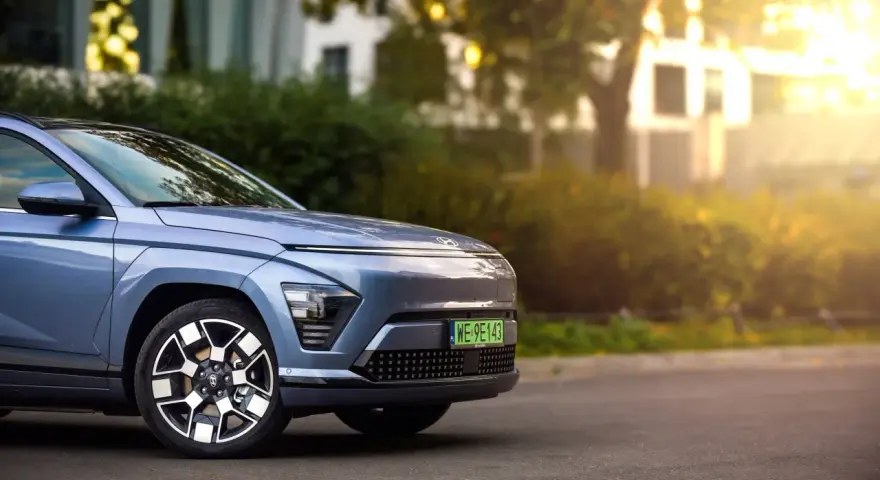 Niebieski Hyundai Kona Electric zaparkowany na ulicy, z widocznym przodem i kołem.
