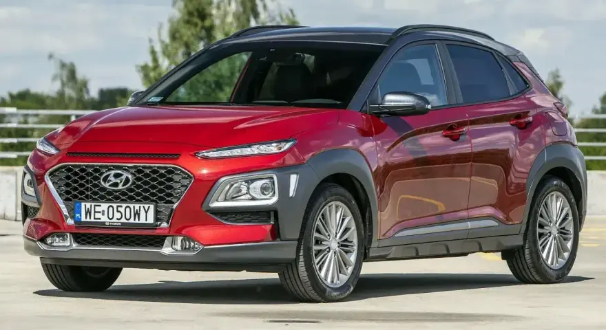 Czerwony, mały SUV Hyundai Kona z czarnym dachem, zaparkowany na zewnątrz.