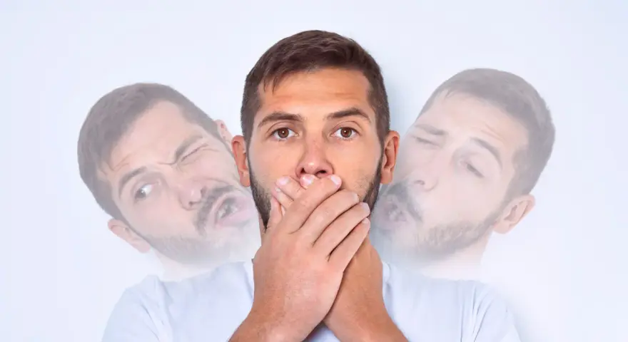 Mężczyzna z zespołem Tourette'a zakrywa usta, próbując powstrzymać tiki.