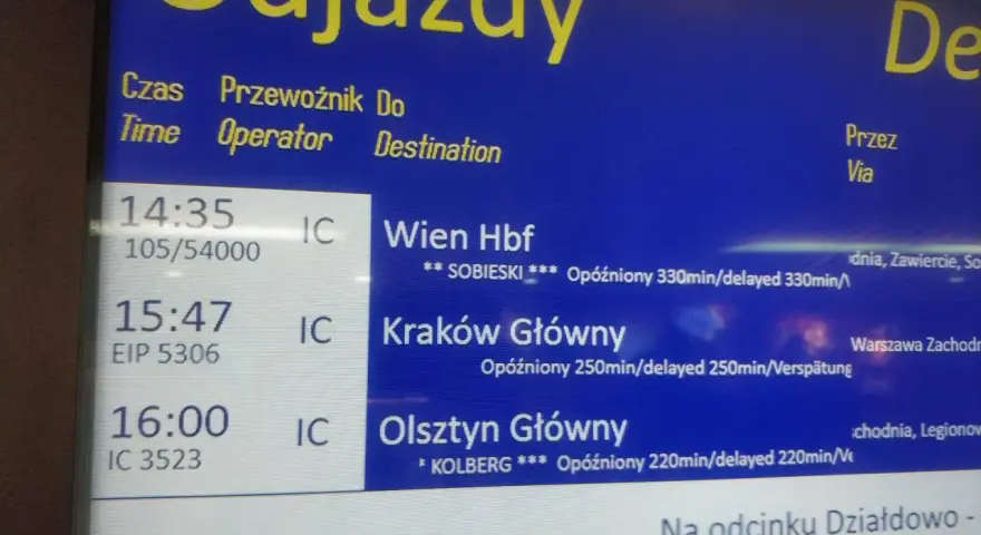 Tablica odjazdów PKP z informacjami o opóźnionych pociągach do Wiednia, Krakowa i Olsztyna.