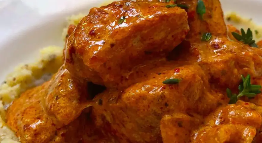 Sabroso pavo en salsa cremosa, adornado con hierbas frescas, servido sobre puré de patatas.