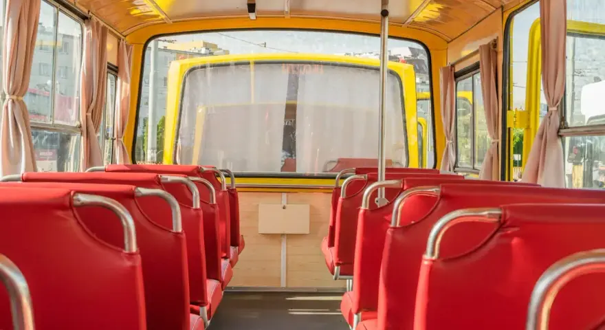 Wnętrze żółtego autobusu z czerwonymi siedzeniami, widok od tyłu.