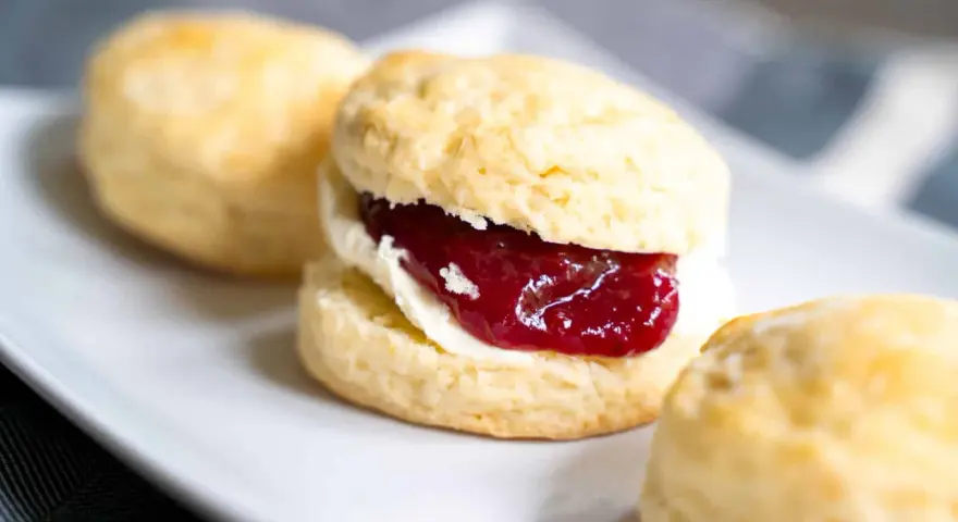 Frisch gebackene Scones mit Clotted Cream und Erdbeermarmelade, ein köstliches Rezept für den Nachmittagstee.