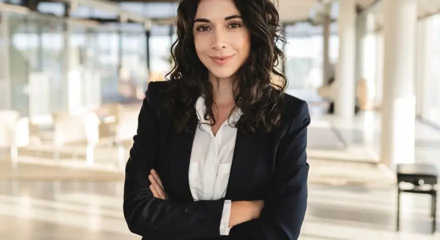 Kobieta w marynarce i białej koszuli, idealnie wpisująca się w **business casual dress code**, pewnie patrzy w obiektyw.