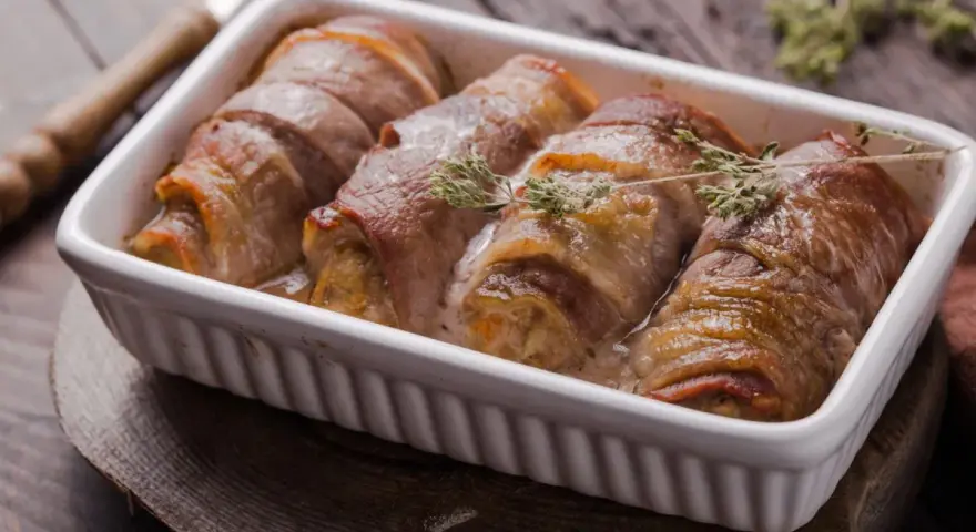 Roladki ze schabu po cygańsku, zawinięte w boczek, pieczone w sosie śmietanowym, ozdobione gałązkami tymianku.