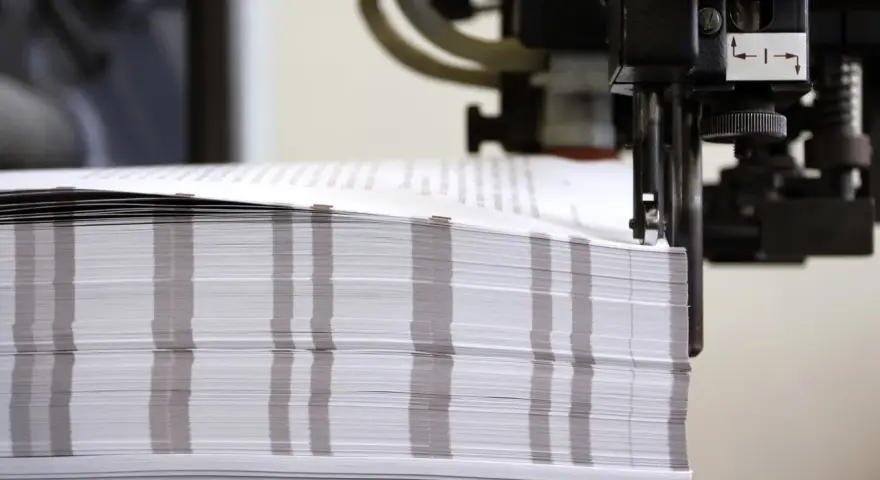 Stos papieru czeka na wykończenie. Powstają tu wydruki fine art, które zachwycą jakością.
