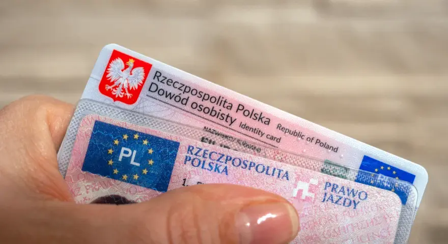 Dłoń trzyma polski dowód osobisty i prawo jazdy.