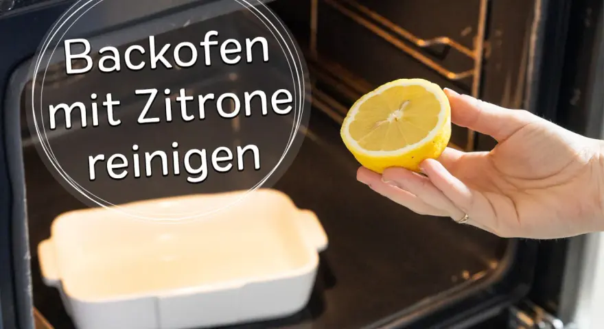 Backofen reinigen mit Zitrone: Eine Hand hält eine halbe Zitrone über eine leere Auflaufform im dunklen Backofen.