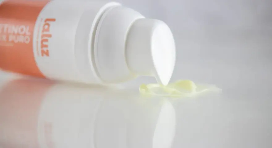 Crema con retinoides que son, de la marca La Luz, con una gota de producto cayendo del dispensador.