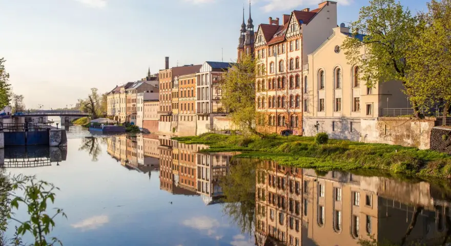 Nad Odrą w Opolu, zabytkowe kamienice odbijają się w wodzie. Spacerując brzegiem, odkryjesz urokliwe zakątki, co można zwiedzić w Opolu.