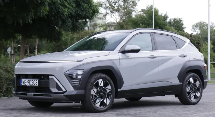Szary Hyundai Kona Hybrid stoi na zewnątrz, z widocznym przodem i bokiem.