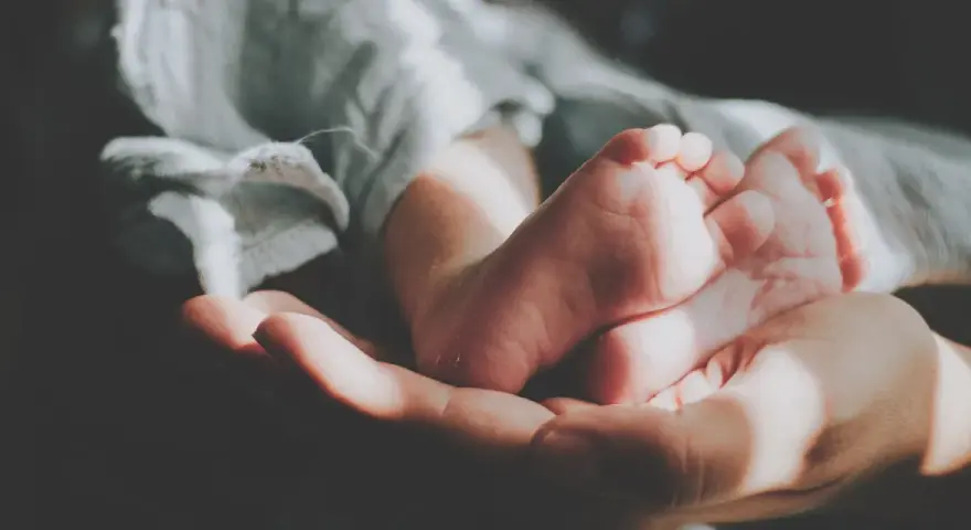 Delikatne stópki dziecka w dłoni, otulone miękkim kocykiem. Idealne dla nich jest pranie w proszku do prania dla dzieci.
