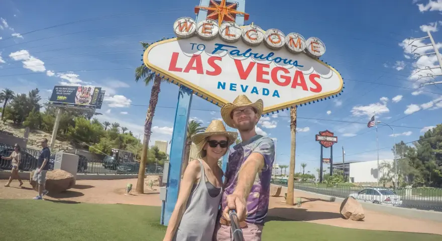 Para co przywieźć ze Stanów? Pamiątkę z Las Vegas! Uśmiechnięta para pozuje do selfie pod słynnym znakiem.