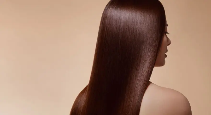 Chevelure soyeuse d'un brun profond, couleur douglas, tombant en cascade sur l'épaule d'une femme.