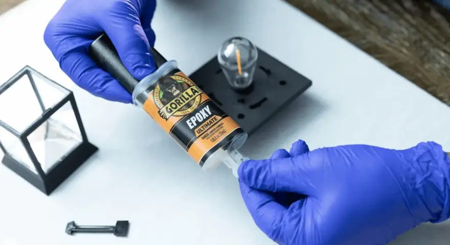 Gloves prepare to apply Gorilla Epoxy, known for its incredible strength, to a small glass and metal object.