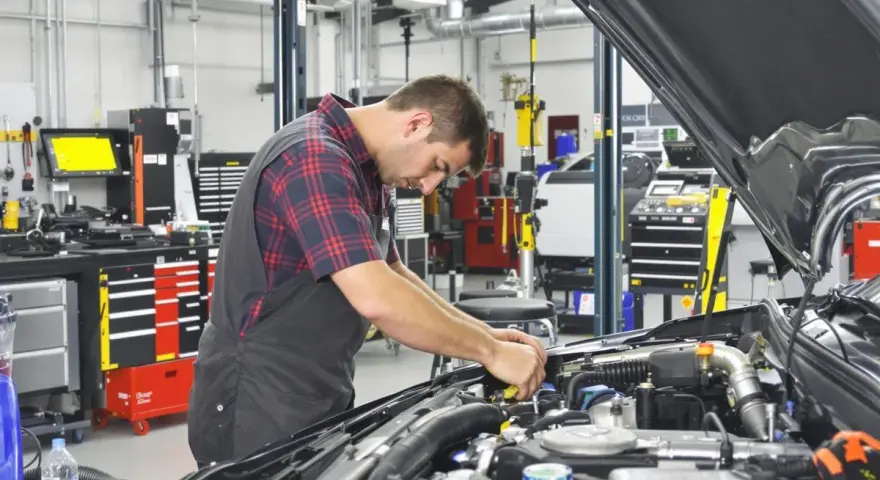 Mecánico trabajando en un motor en un taller. El sistema ERP del taller está organizado y listo para el diagnóstico.