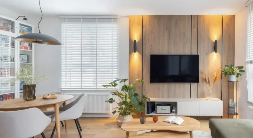 Przytulny salon inspiracje: drewniana ściana z TV, jadalnia, wygodne fotele i stoliki kawowe tworzą ciepłą atmosferę.