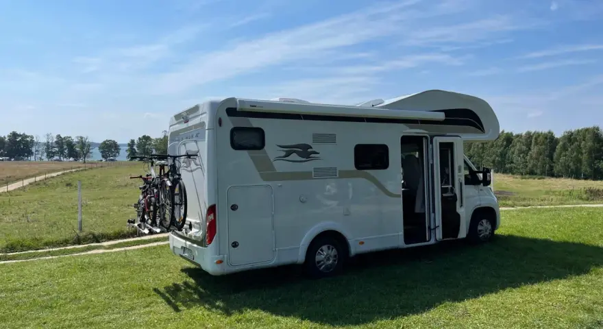 Kamper na trawie, gotowy na wakacje. To ekskluzywne pole namiotowe Mazury oferuje ciszę i piękne widoki na jezioro.