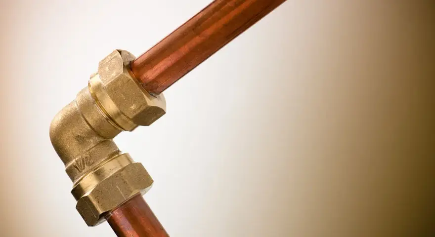 Un coude en laiton relie deux tuyaux en cuivre. Ce raccord per cuivre est essentiel pour les installations de plomberie.