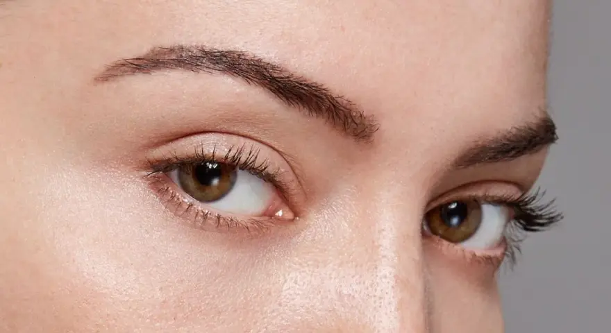 Gros plan sur des yeux aux cils longs et recourbés, encadrés par des sourcils aux forme sourcils parfaits.