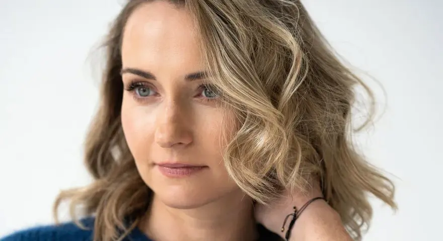 Zuzanna Irena Grabowska z burzą blond włosów i niebieskimi oczami, w granatowym swetrze.