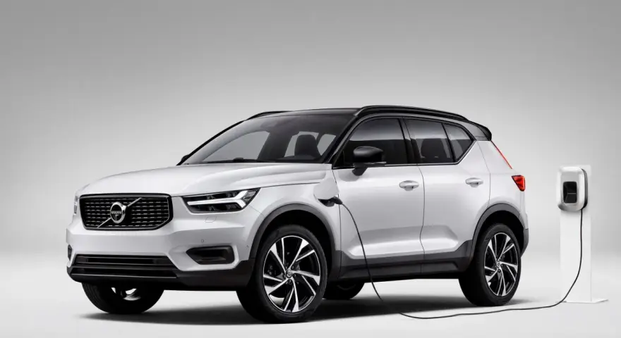 Biały Volvo XC40 Recharge plug-in hybrid podłączony do ładowarki.