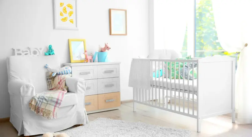 Stanza luminosa con lettino bianco, poltrona comoda e decorazioni a tema neonato. Un nido accogliente per un piccolo tesoro.