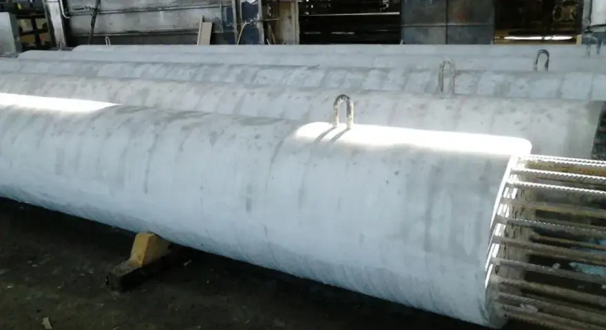 Długie, betonowe rury leżą obok siebie. Widać metalowe uchwyty do transportu. To efekt pracy z szalunkiem papierowym, który nadał im idealny kształt.