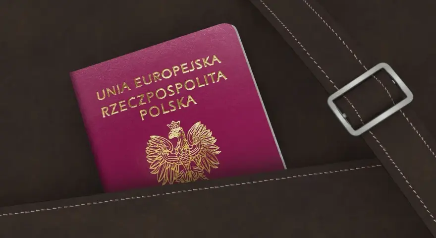 Nowy polski paszport w kolorze fuksji z godłem orła w złocie, schowany w brązowej skórzanej kieszeni.
