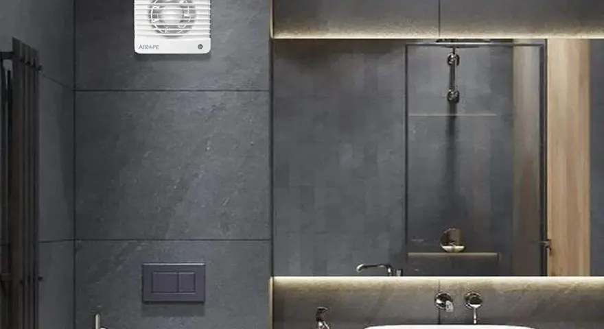 Extractor de baño blanco instalado en pared de azulejos grises.