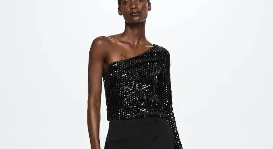 Top negro de lentejuelas asimétrico, ideal para saber como vestir para un cumpleaños de noche mujer.