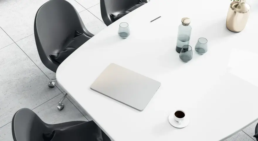 Tavolo da riunione con laptop, bicchieri d'acqua, caffè e un vaso di fiori. Ideale per un ingegnere gestionale lavoro.
