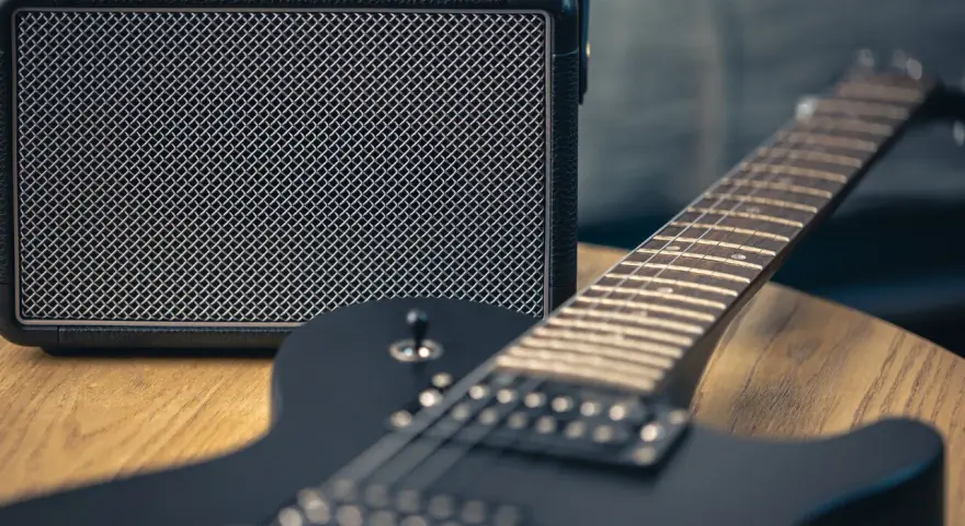 Czarna gitara elektryczna i mały wzmacniacz – to podstawa, co jest potrzebne do gitary elektrycznej, by zacząć grać.