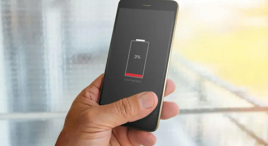 En hand håller en mobil med 3% batteri. Bakgrunden visar suddiga appaktiviteter.